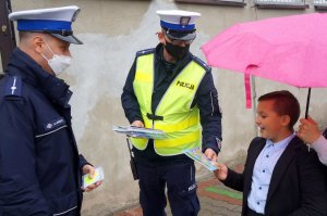 policjanci wręczają chłopczykowi kolorowankę