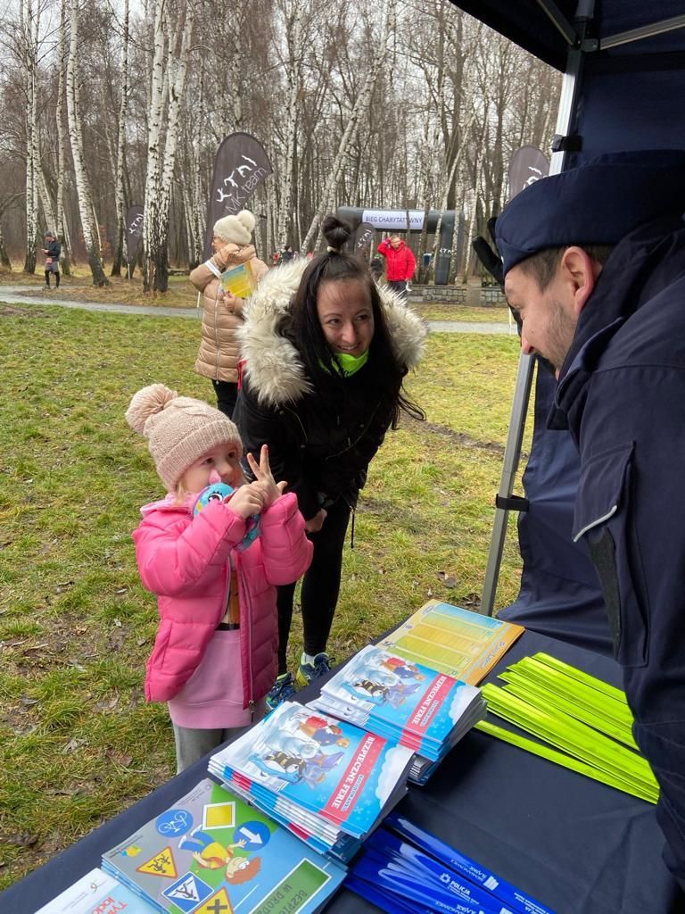 policjant przy stanowisku profilaktycznym rozmawia z dziewczynką