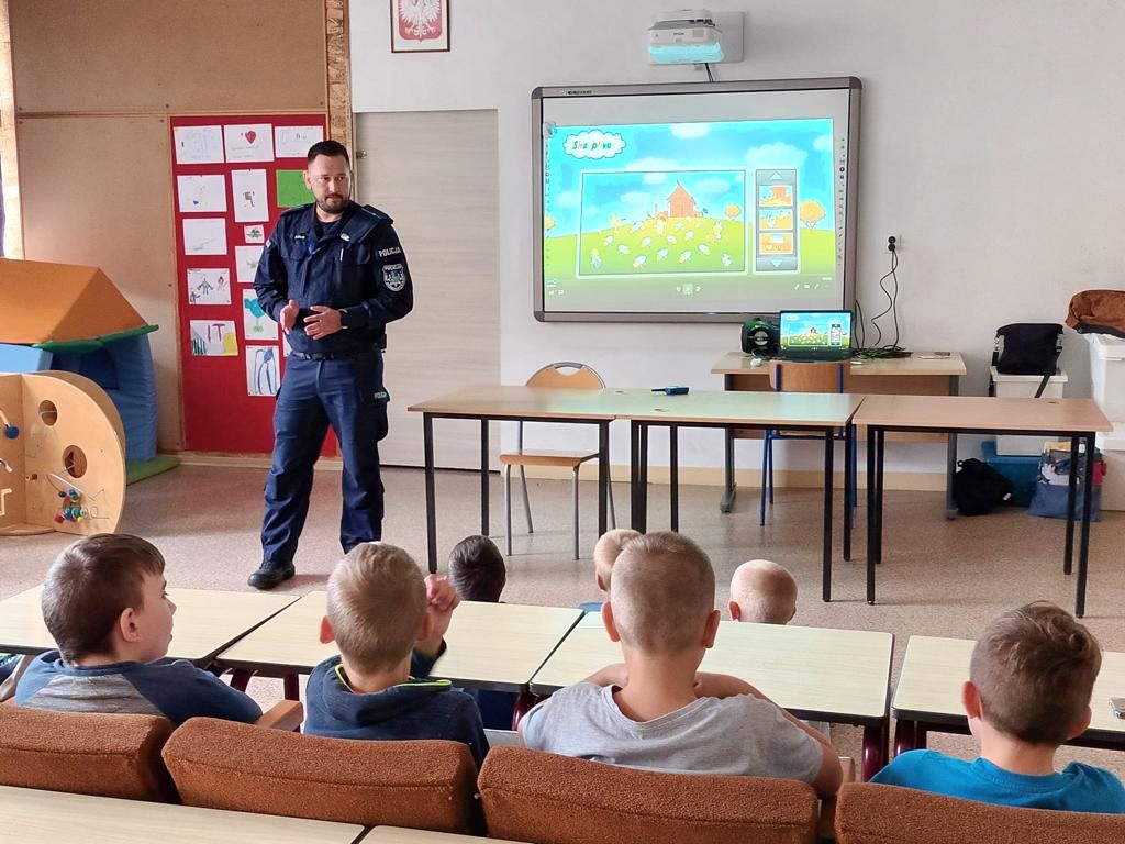 policjant stoi w klasie przy rzutniku