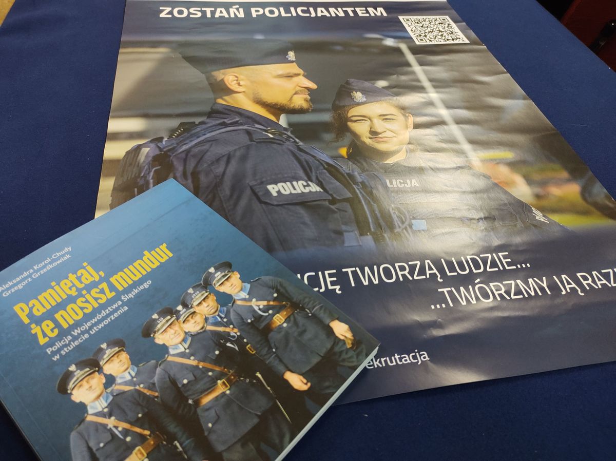 na zdjęciu plakat "Zostań policjantem" i książka