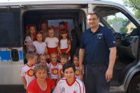 policjant z przedszkolakami i radiowóz
