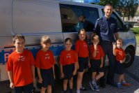 policjant z przedszkolakami i radiowóz