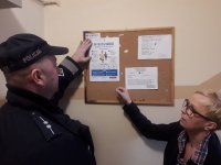 policjant rozwiesza plakaty na tablicy
