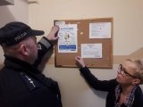 policjant rozwiesza plakaty na tablicy