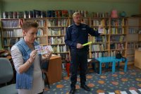 policjant z panią bibliotekarką trzymają karteczki z numerami alarmowymi