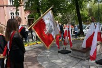 uczniowie ze sztandarem przed pomnikiem
