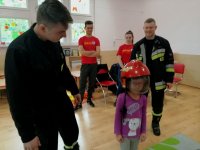 strażacy z przedszkolakiem ubranym w kask strażacki