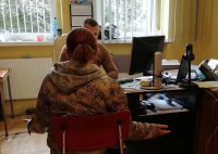 podejrzana siedzi przy biurku, policjant ją przesłuchuje