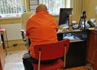 podejrzany siedzi przy biurku, policjant go przesłuchuje