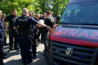 policjanci umundurowani stoją obok wozu strażackiego i rozmawiają