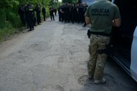 policjant przy samochodzie, a za nim policjanci