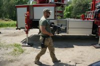 policjant idzie i trzyma drona, w tle wóz straży