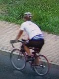 mężczyzna w białej koszulce na czerwonym rowerze.