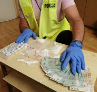 policjant w rękawiczkach i rozłożone w woreczkach i aluminiowych kulkach narkotyki