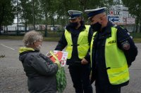 policjanci wręczają laurkę i odblask kobiecie