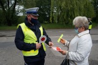 policjant wręcza kobiecie laurkę i odblask