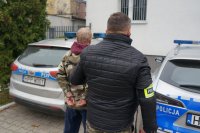 policjant stoi z zatrzymanym przy radiowozie