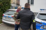 policjant stoi z zatrzymanym przy radiowozie