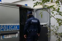 policjant stoi przy drzwiach radiowozu