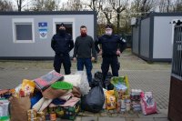 policjanci z przedstawicielem schroniska stoją przy radiowozie i zebranych darach