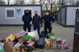 policjanci z przedstawicielem schroniska stoją przy radiowozie i zebranych darach