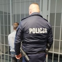 policjant stoi z podejrzanym przy drzwiach z celi