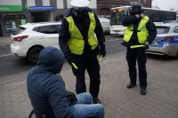 policjanci wręczają odblaski osobie na wózku inwalidzkim