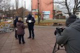 policjanci rozdają koperty życia mieszkankom, obok kamera która rejestruje nagranie