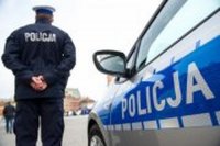 policjant stoi obok radiowozu