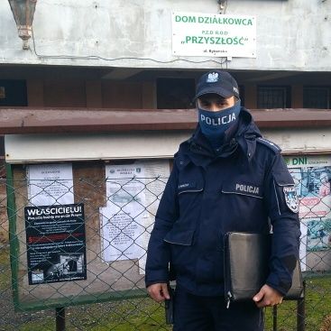 dzielnicowy przy tablicy informacyjnej, na której umieścił plakat