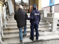 policjant idzie po schodach z podejrzanym