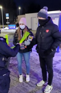 policjantka wręcza opaski odblaskowe wolontariuszom