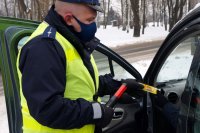 policjant z drogówki wręcza kierowcy alkotest