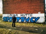 policjant stoi przy budynku, na którym namalowano graffiti
