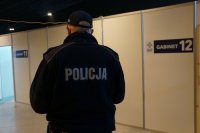 policjant stoi przed drzwiami do punktu szczepień