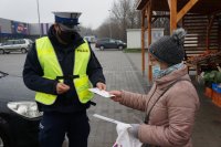 policjant wręcza opaski odblaskowe kobiecie