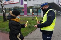 policjant wręcza opaski odblaskowe kobiecie