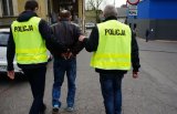 policjanci prowadzą zakutego w kajdanki podejrzanego