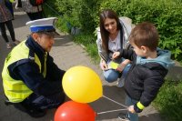 policjant wręcza dziecku odblask, które trzyma balony