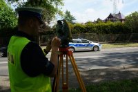 policjant wykonuje pomiary tachimetrem