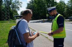 policjant wręcza mężczyźnie opaskę odblaskową