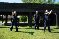 policjanci na strzelnicy z bronią wycelowaną w trenażery i instruktorem