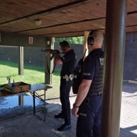 policjant strzela z broni długiej, obok stoi instruktor