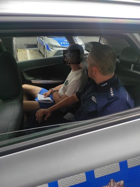policjant w radiowozie siedzi obok podejrzanego