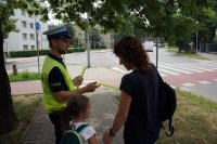 policjant wręcza opaski odblaskowe pieszym