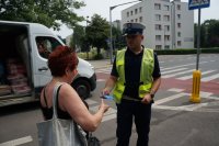 policjant wręcza opaski odblaskowe pieszym