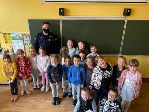 policjant stoi z dziećmi- zdjęcie grupowe