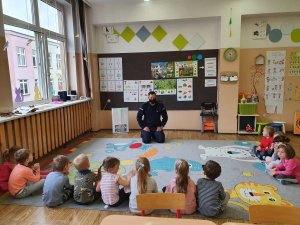 policjant siedzi i rozmawia z przedszkolakami