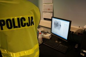 technik policyjny przy monitorze z daktyloskopią