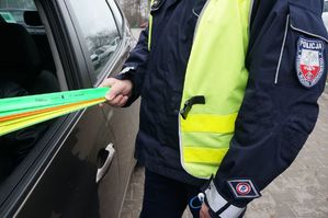 policjant trzyma opaski odblaskowe